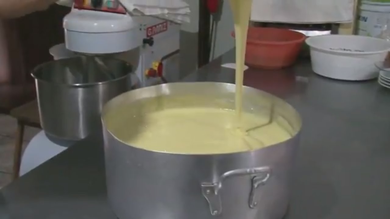 Panela com bastante queijo sendo mexido por colher 