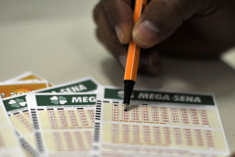 Bilhetes da mega-sena sendo assinalados com uma caneta Bilhetes da mega-sena sendo assinalados com uma caneta