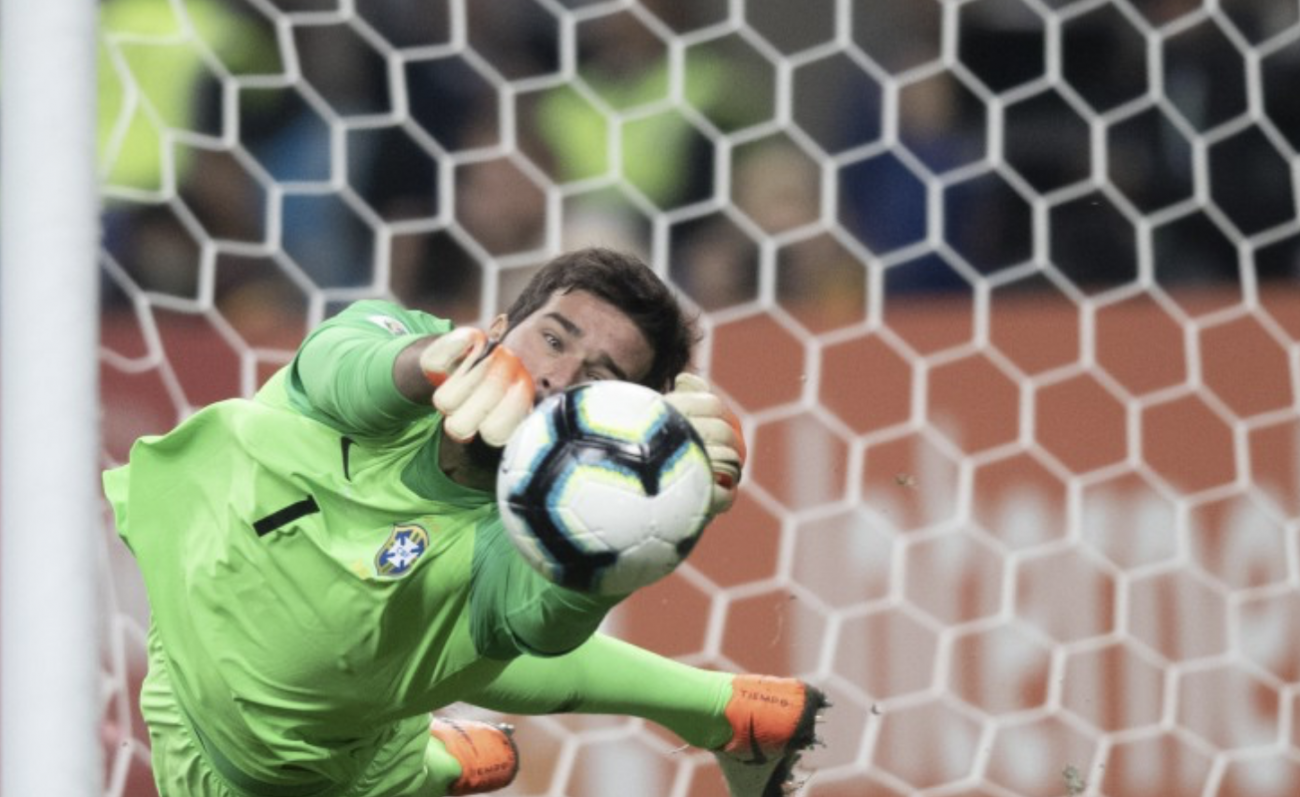 Logo na primeira cobrança, Alisson saltou para defender, dando um sinal do que seria o resultado da noite. - Lucas Figueiredo/CBF