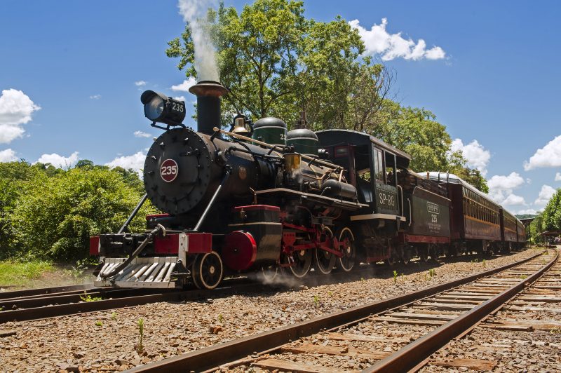 Trem em rodovia e céu com poucas nuvens