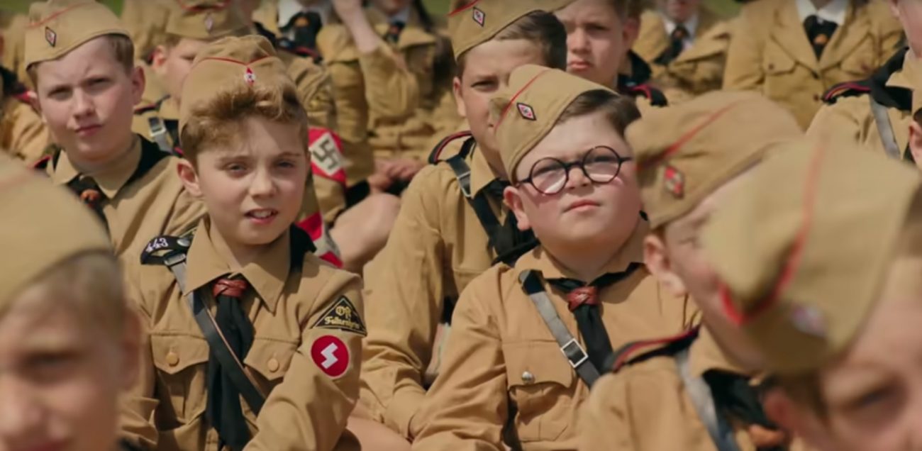 Certo dia, Jojo descobre que a mãe (Scarlett Johansson) está escondendo uma judia (Thomasin McKenzie) no sótão de casa. Depois de várias tentativas frustradas para expulsá-la, o jovem rebelde começa a desenvolver empatia pela nova hóspede. A produção tem direção de Taika Waititi. - Foto: Reprodução/Redes Sociais/ND