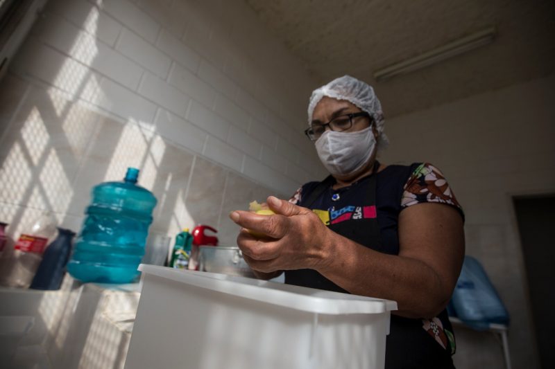 Voluntária ajuda a preparar a refeição doada aos moradores mais vulneráveis do bairro – Foto: Anderson Coelho/ND