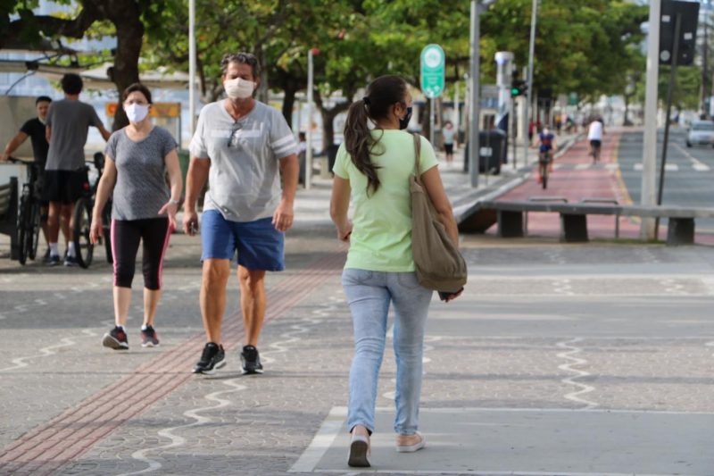 Pessoas caminhando na calçada de máscara
