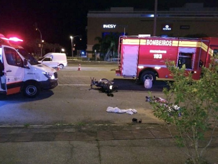 Acidente mostra uma moto no chão, ambulância e corpo de bombeiros. Ao fundo está o shopping Iguatemi