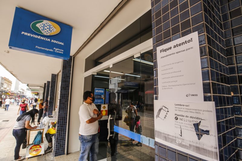Agência do INSS. Uma pessoa aguarda no lado de fora para ser atendido