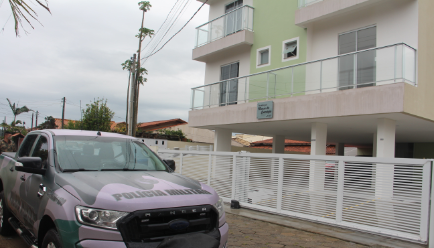 Um carro da Polícia Militar ao lado de um prédio