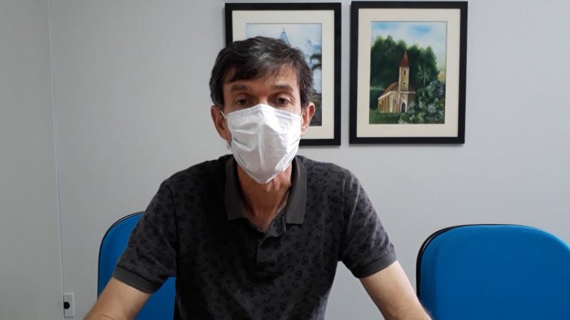 Foto do presidente da AMAVI. É um homem de cabelo grisalho e de máscara. Ele está sentado em uma cadeira azul e no fundo tem uma parede branca com dois quadros de paisagem.