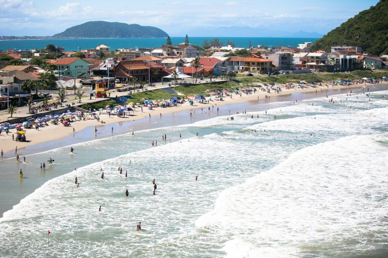 Praia com ondas quebrando com outra praia ao fundo em vista aérea 