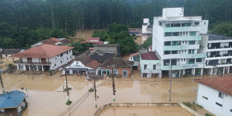 Foto de uma cidade alagada, com entulhos presos em alguns imóveis. 