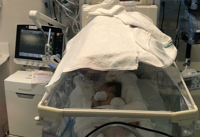 Imagem do bebê dentro da UTI com diversos equipamentos ao redor dele.