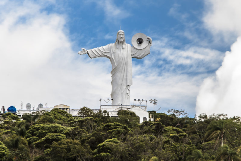 Cristo luz visto de baixo, aparecendo as árvores em baixo e céu em cima