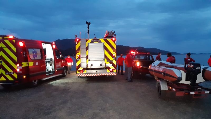 Carros do Corpo de bombeiros, um bote inflável e pessoas vestidas de vermelho