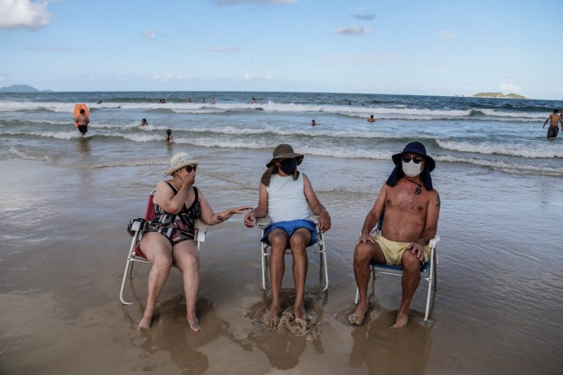 Idosos usam máscara para aproveitar a praia e o sol nos Ingleses, em Florianópolis