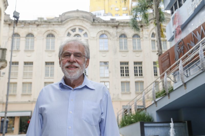 Renato da Farmácia, de camisa social azul claro, em frente a prédio histórico