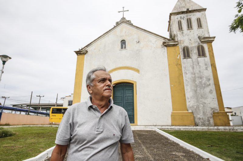 Dalmo Meneses (DEM), de camisa cinza, em frente a uma igreja típica de Florianópolis