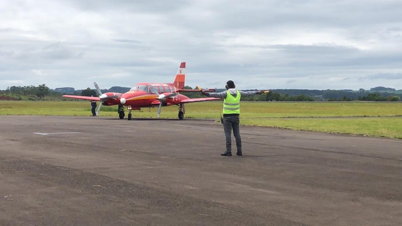 avião vermelho pousando no aeroporto em chapecó com balizador de colete verde na frente