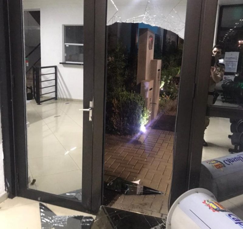 porta com vidraças quebradas e vidros espalhados pelo chão