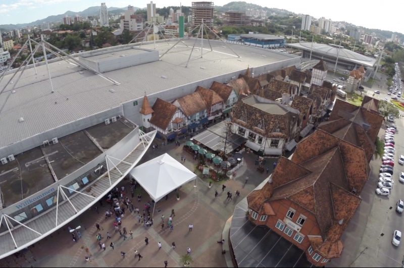 Espaço da Vila Germânica em Blumenau, visto de cima, com os telhados a mostra e pessoas caminhando