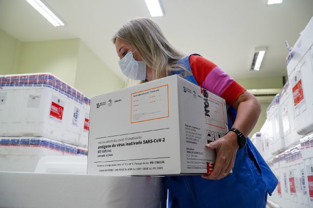 mulher segura caixa com as doses da vacina