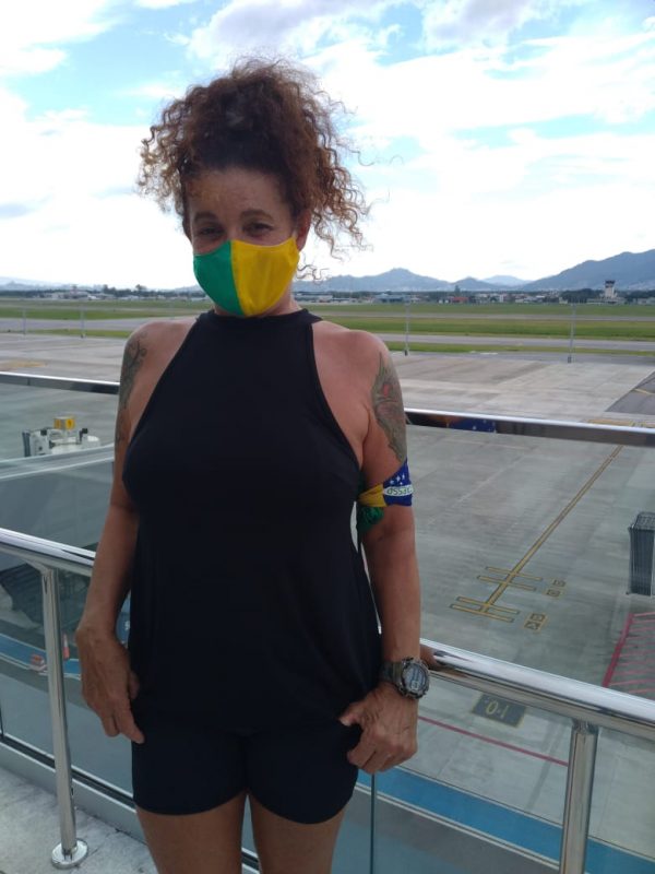 Elizabeth Goulart, mulher de camisa preta e máscara verde e amarela