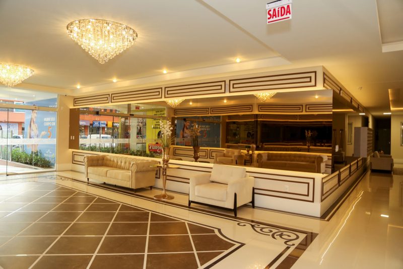 Iluminação de destaque, grande área espelhada e piso com padrão diferenciado chamam atenção no hall do <a href="http://www.amconstrucoes.com.br/empreendimentos/dolce-vitta/" target="_blank" rel="noopener noreferrer">condomínio Dolce Vitta</a>, em Palhoça – Foto: AM Construções/Divulgação
