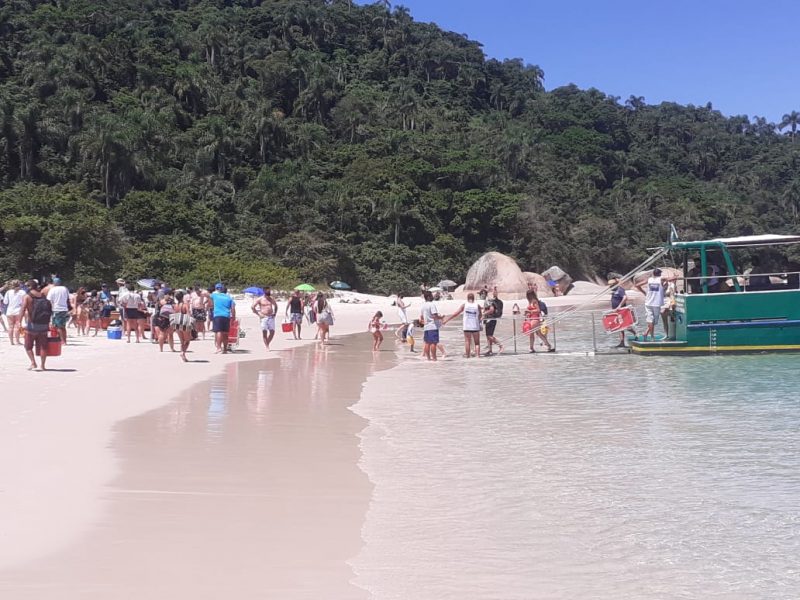 Pessoas descendo de embarcação na praia