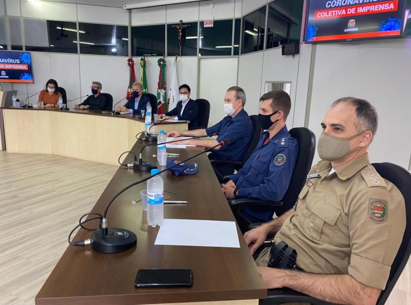 Coletiva de imprensa realizada para atualização das medidas de combate à Covid-19 em Xanxerê, Na imagem aparece sete pessoas sentadas em um auditório. Entre eles está o prefeito de Xanxerê Oscar Martarello e demais autoridades da saúde e de segurança do município. 