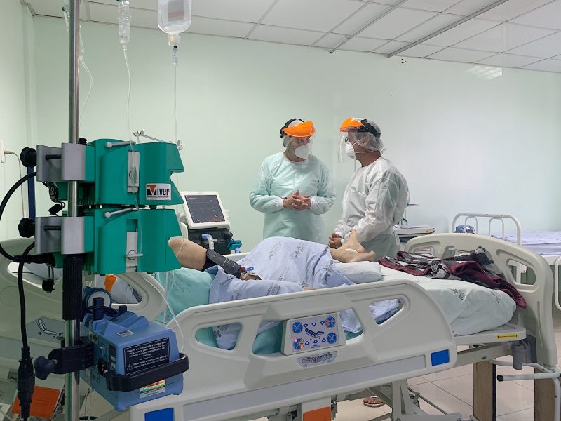 Leito de UTI com paciente e médicos ao redor