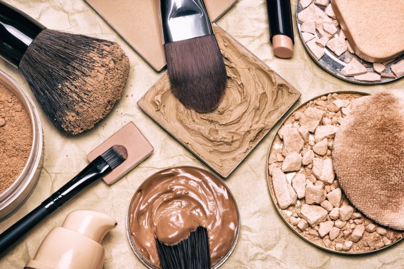 -Foto: Produtos de de beleza, esses do setor de Make Up, dentre eles, base, corretivo, iluminador, blush, base, pincéis, e lip gloss.