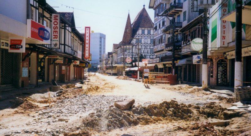 A reurbanização da rua XV de Novembro foi a primeira obra de grandes proporções na via desde que ela ganhou paralelepípedos em 1929. Depois disso, foram feitas apenas algumas intervenções para a implantação do sistema de águas pluviais e esgoto, energia elétrica e telefonia. Fora a verticalização das construções e pequenas alterações no paisagismo, o traçado da histórica via pouco mudou. O projeto de reurbanização foi executado e elaborado pelos arquitetos Armando Ito e Roberto Sabatella, de Curitiba. Na imagem, vemos a obra com a retirada completa do antigo calçamento. – Fonte e foto: Fundação Cultural de Blumenau / Arquivo Histórico José Ferreira da Silva