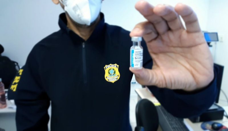 Policial segurando a vacina