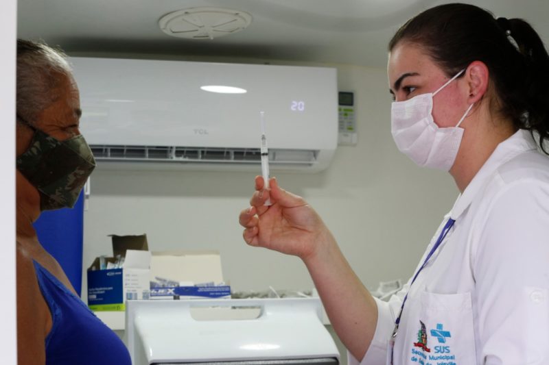 Enfermeira mostra dose da vacina para mulher