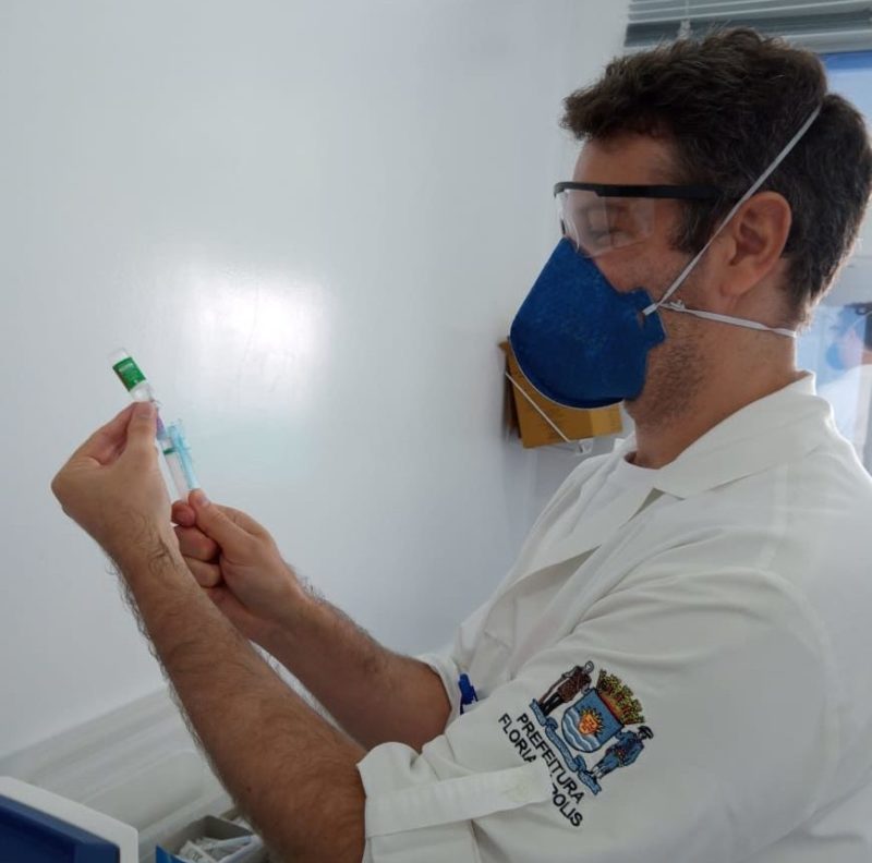 enfermeiro colocando insumo da vacina na seringa