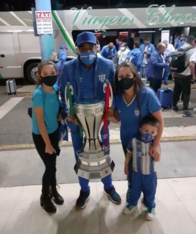 No aeroporto de Chapec&oacute;, Bet&atilde;o (com a Ta&ccedil;a) ao lado de Andreia Balestreri, vi&uacute;va de M&aacute;rcio Bonsfiled, um avaiano fan&aacute;tico e falecido recentemente, com as crian&ccedil;as Lu&iacute;za e Lucas. – Foto: Andreia Balestreri/acervo familiar