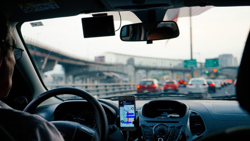 Motorista de aplicativo em carro em meio a congestionamento na rua