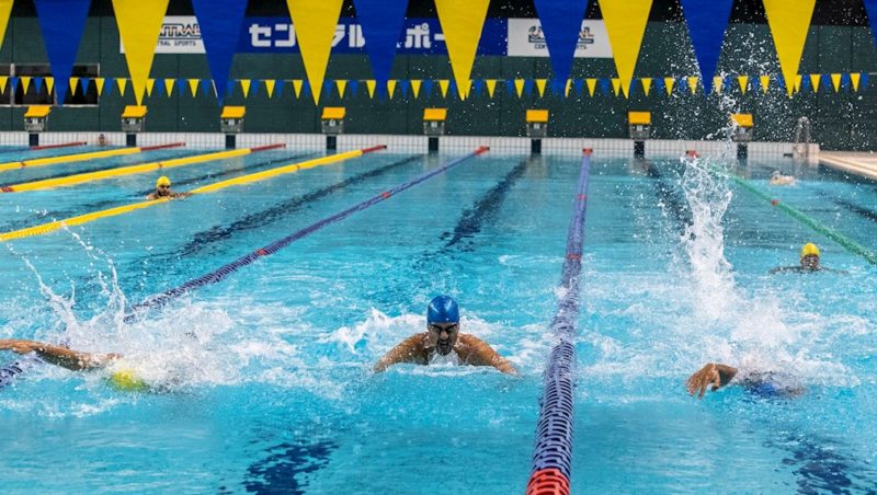 Imagem mostra nadadores em pista de natação e no fim placa escrita em mandarim