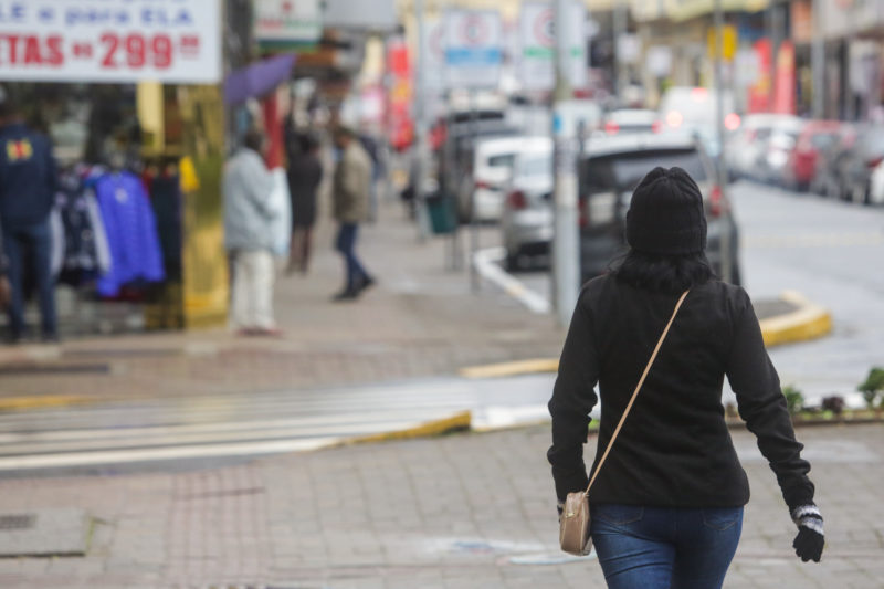 mulher de casaco atravessa a rua em joinville