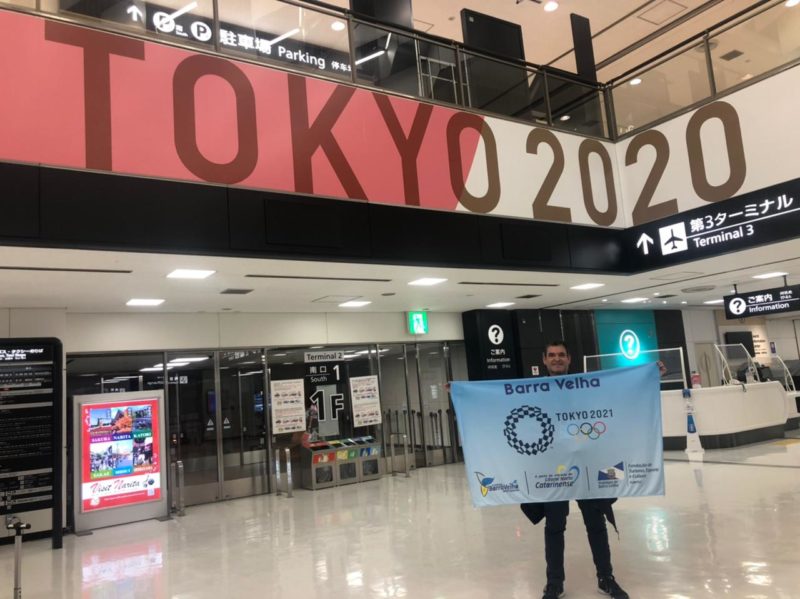 Salvio Sedrez, em sua segunda edi&ccedil;&atilde;o de Jogos Ol&iacute;mpicos, com a bandeira referente a Barra Velha: amor pela cidade que o acolheu h&aacute; mais de 40 anos – Foto: Divulga&ccedil;&atilde;o/ND