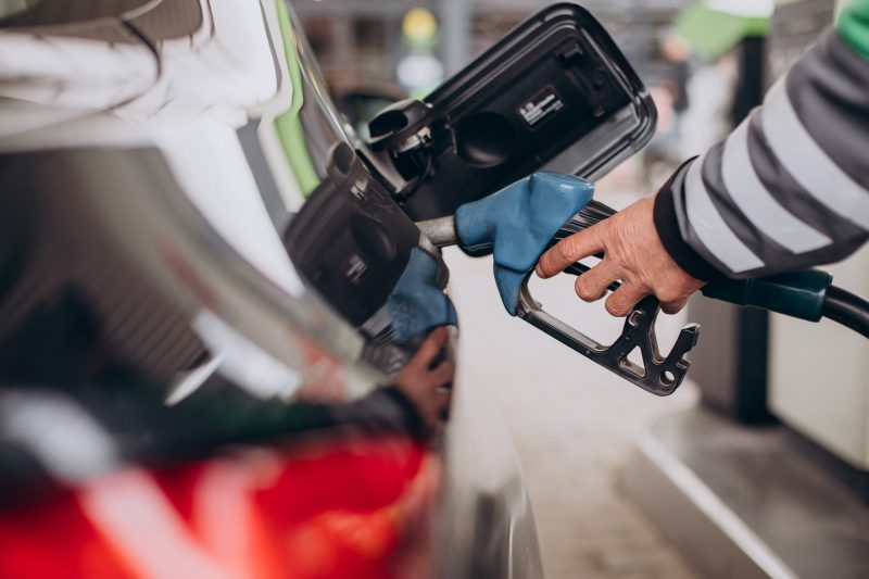 Imagem mostra pistola de gasolina no carro e uma mão segurando enquanto abastece