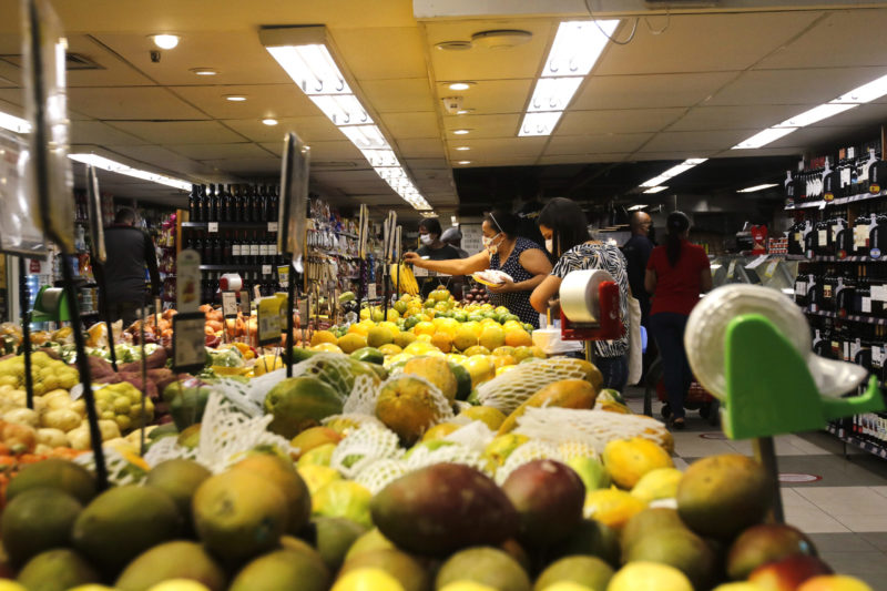 Imagem mostra uma fila de frutas e uma pessoa pegando um mamão no fim da imagem, expectativa do uso é referenciar o aumento nos preços em SC