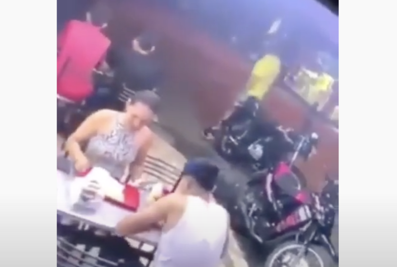 Casal lanchando durante a chegada dos bandidos, ao fundo – Foto: Reprodu&ccedil;&atilde;o