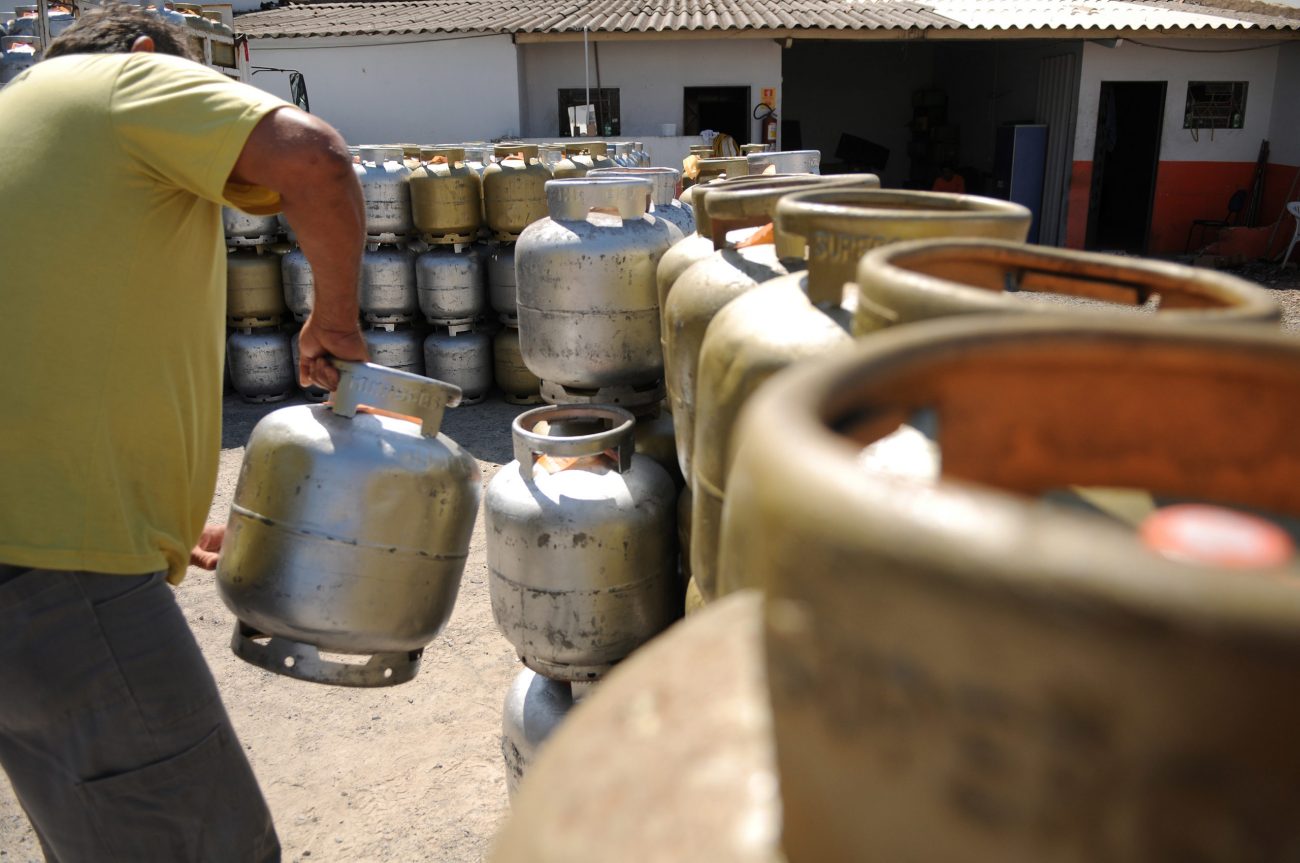 Trabalhador organiza botijões no pátio de distribuidora Trabalhador organiza botijões no pátio de distribuidora