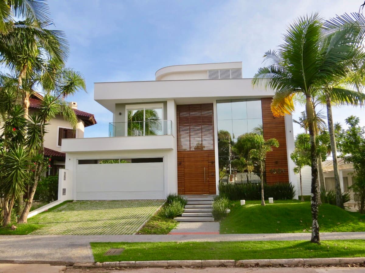 na foto é possível ver uma casa na praia branca com detalhes em madeira, com um jardim na frente.