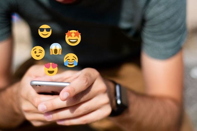 Homem sentado segurando celular com emojis