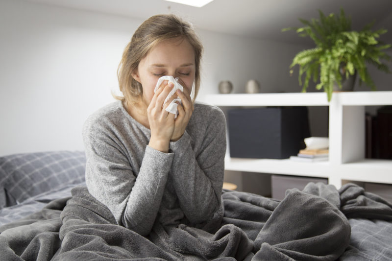 Mulher sentada em uma cama apresentando doença respiratória