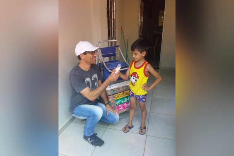 Emerson entregando um geladinho para um menino