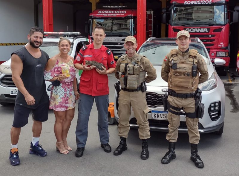 Bombeiros responsáveis pelo resgate do gato e os novos tutores posam para foto com o animal