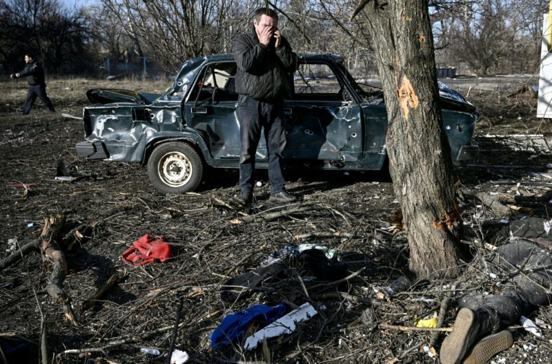 Um homem reagindo no telefone enquanto est&aacute; de p&eacute; pr&oacute;ximo a corpo esticado no ch&atilde;o ap&oacute;s bombardeio na cidade de Chuguiv – Foto: Aris Messinis/AFP/ND