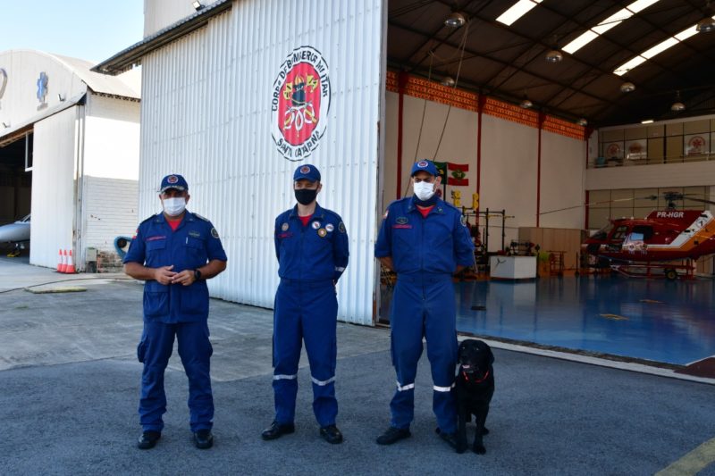 Nesta imagem, est&atilde;o o Comandante-Geral do CBMSC, coronel Marcos Aur&eacute;lio Barcelos; o Capit&atilde;o Alan, que comandar&aacute; a opera&ccedil;&atilde;o, e o bin&ocirc;mio mais experiente da equipe, Cabo Ronaldo Fumagalli e o c&atilde;o Hunter – Foto: CBMSC/Divulga&ccedil;&atilde;o/ND