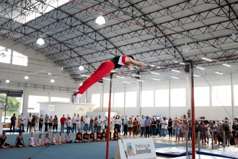 A foto mostra um atleta em uma barra de ferro
